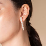 Discover the allure of Stella Piercing: a woman captivating in a white dress and stunning earrings.