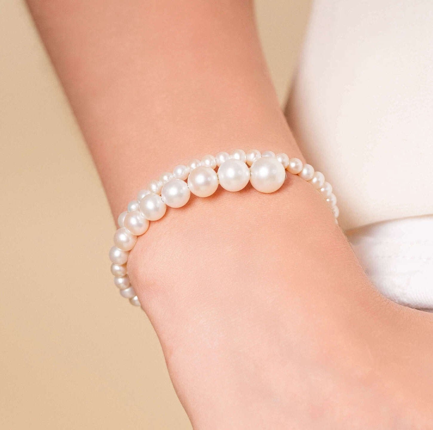 Stylish woman in white jeans accessorized with a chic Spiral Pearl Bracelet.