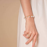 Elegant woman in white dress with Pearl Dot x Gold Bracelet.