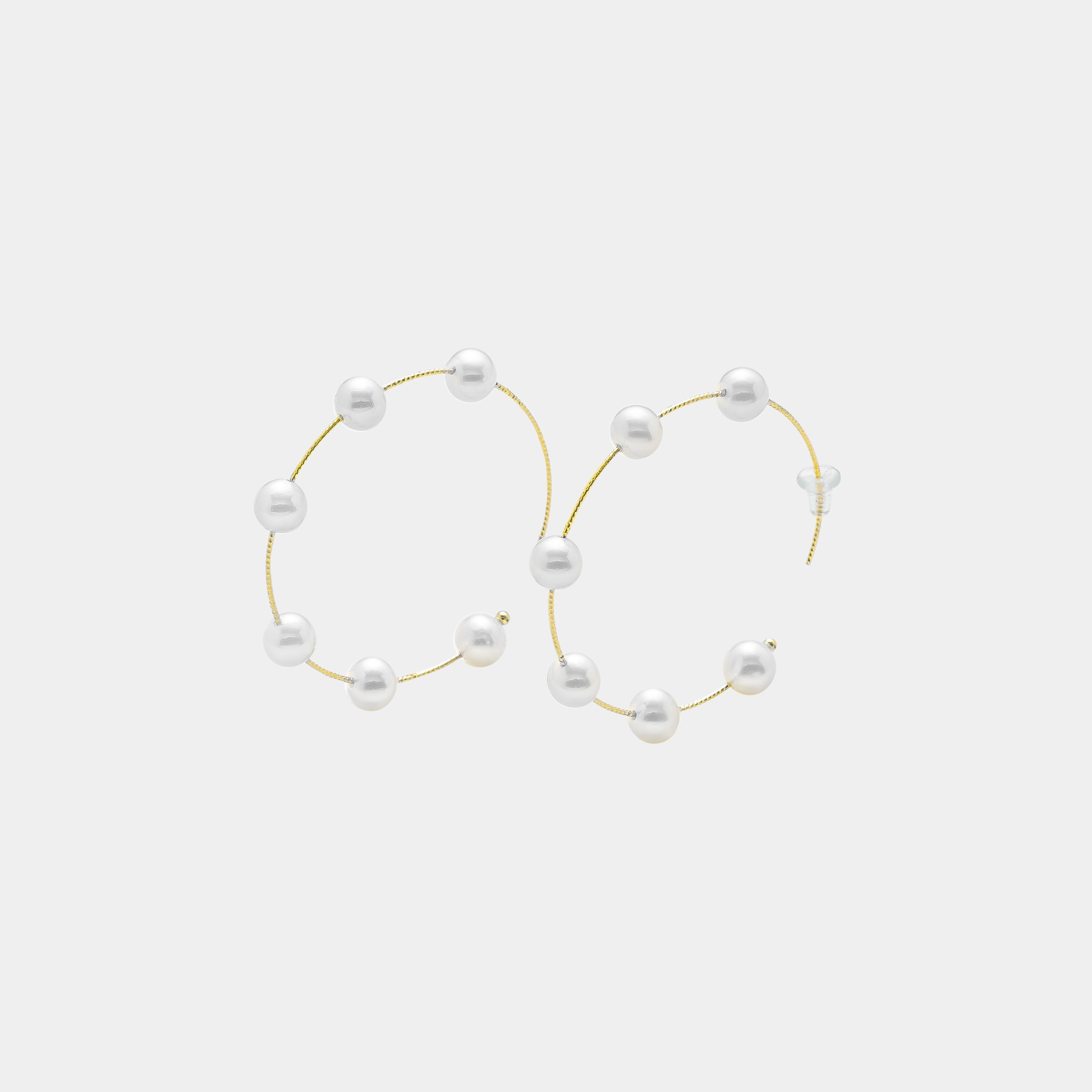 Embrace sophistication with these captivating gold hoop earrings embellished with delicate white pearls. A must-have for any jewelry collection.