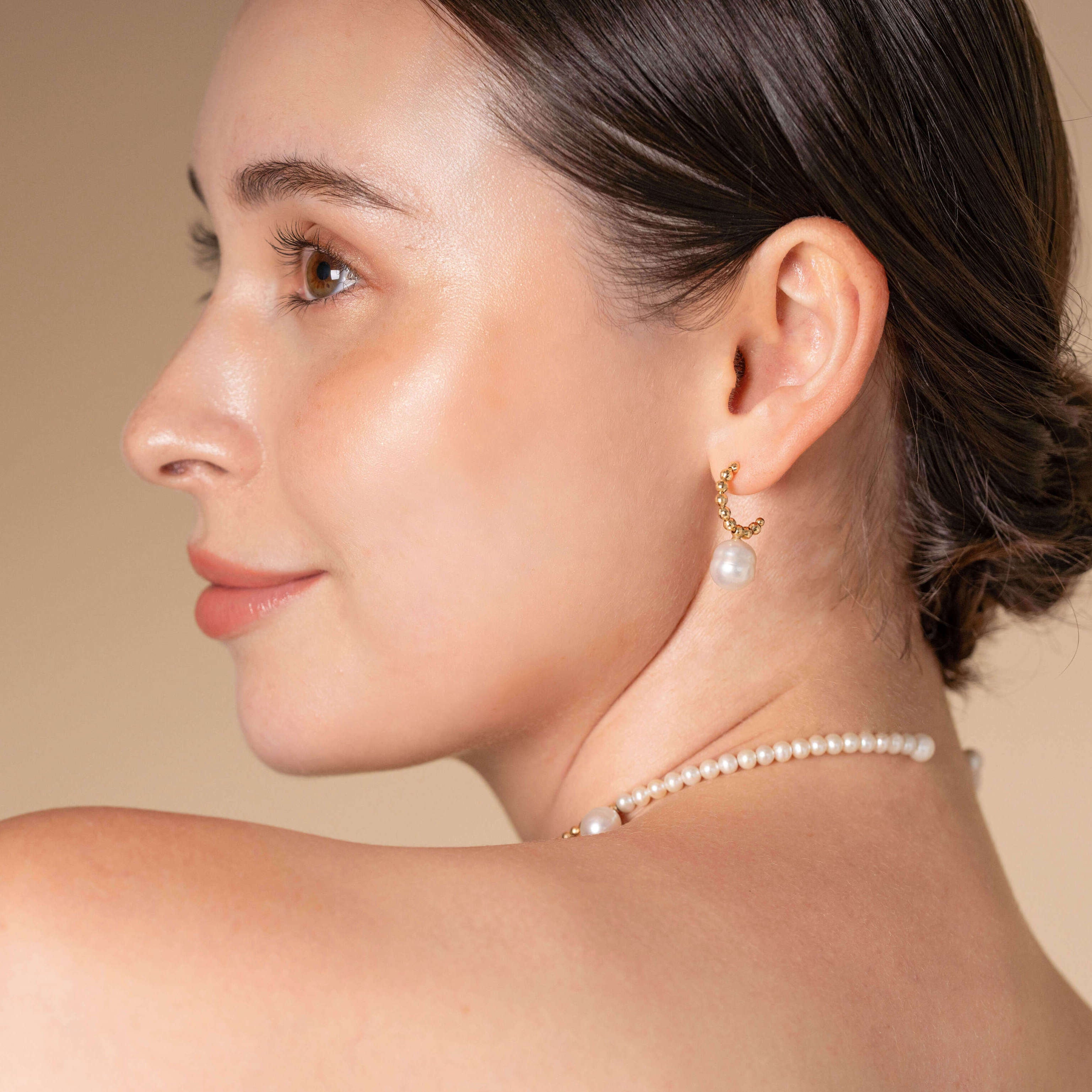 A woman adorned with stunning South Sea pearl earrings crafted in 18K yellow gold, epitomizing luxury and grace.