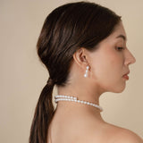 Upgrade your outfit with a stylish black top and beautiful pearl earrings on a woman. Classic and fashionable!