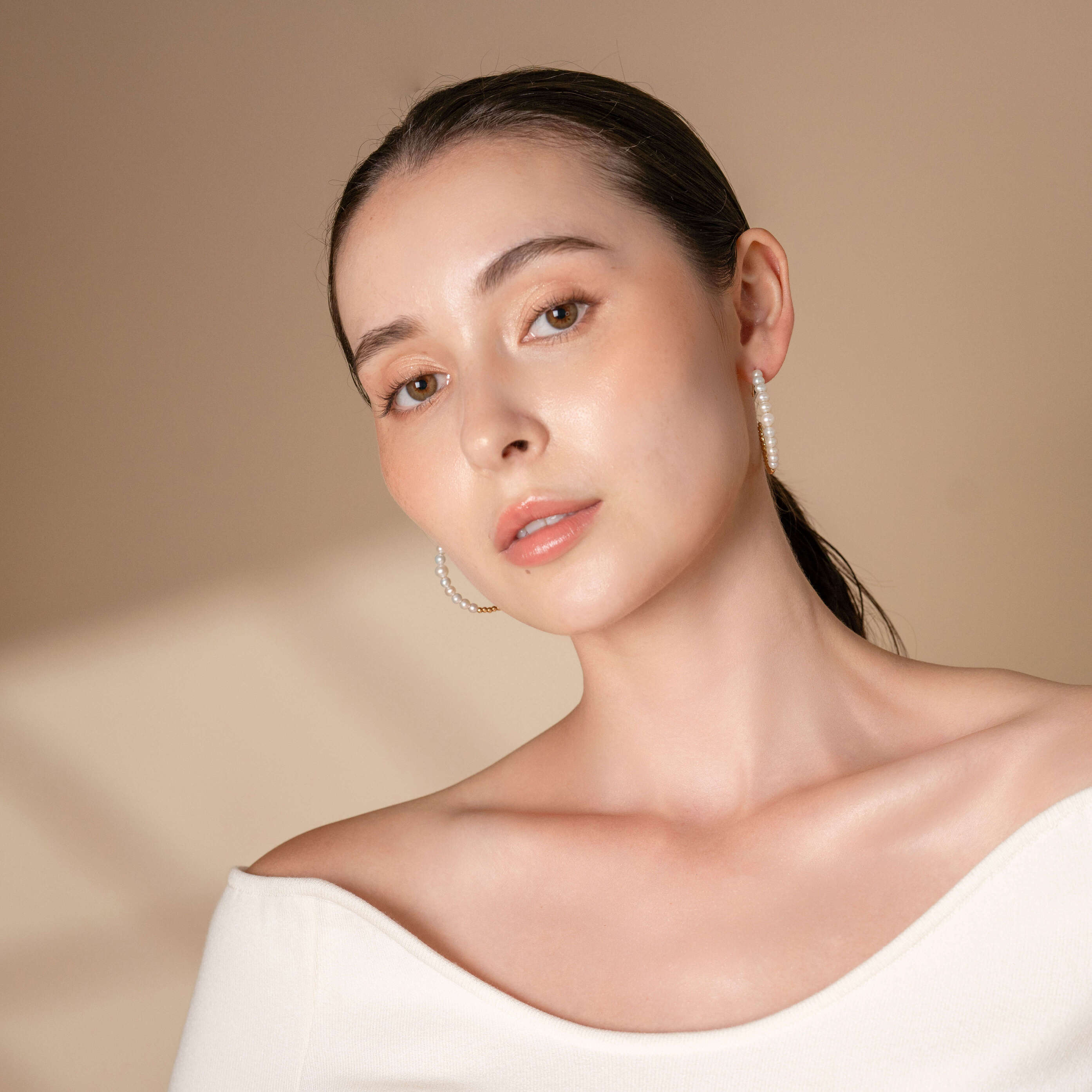 Stylish woman in white top and earrings, Mirror Gold x Pearl Hoop Pierce accessory.