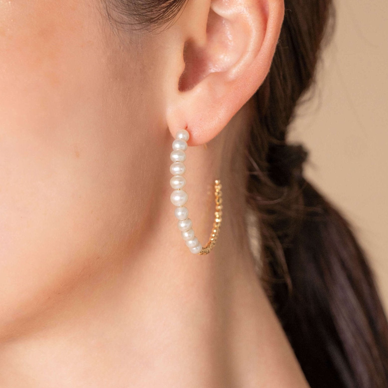 Chic woman in white top accessorized with Mirror Gold x Pearl Hoop Pierce earrings.