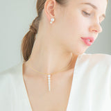 A woman dons a white top, highlighted by a sophisticated necklace of freshwater pearls and 18K yellow gold.