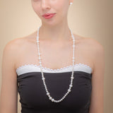 A woman elegantly showcases a long freshwater pearl necklace with a silver clasp, radiating timeless beauty and sophistication.