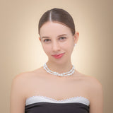 Elegant woman in a black dress, showcasing a long freshwater pearl necklace with a silver clasp, radiating sophistication.