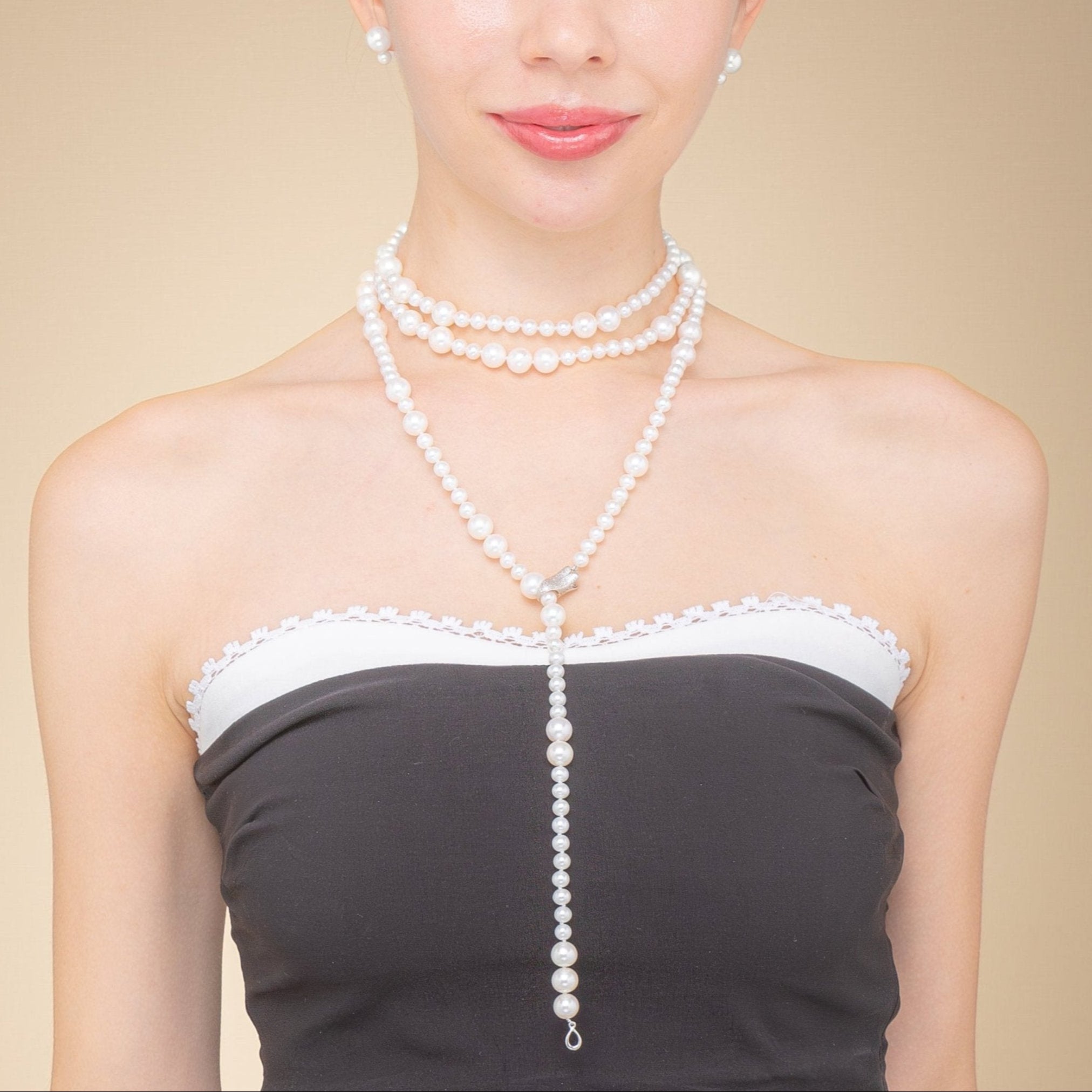 A woman wears a long freshwater pearl necklace with a silver clasp, embodying elegance and the allure of classic jewelry.