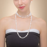 A woman elegantly showcases a long freshwater pearl necklace with a silver clasp, radiating timeless beauty and sophistication.